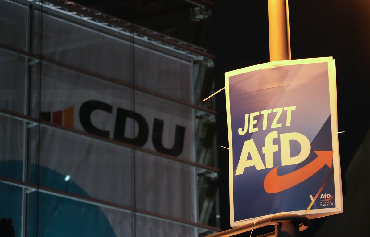 Плакат AfD на фоне логотипа партии CDU в Берлине, 30 января 2025 года. Фото: Manuel Genolet / dpa / picture-alliance / Scanpix / LETA