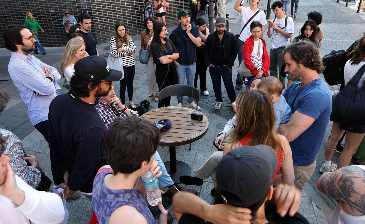 Люди собираются вокруг радиоприёмника на улице в центре Мадрида, 28 апреля 2025 года. Фото: Thomas Coex / AFP / Scanpix / LETA