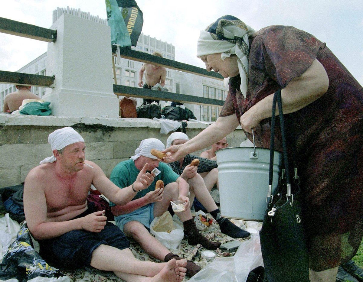 Пожилая женщина подкармливает бастующих шахтеров перед Домом правительства России, 13 июня 1998 года. Фото: Илья Питалев / EPA