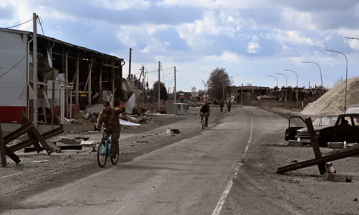 Люди в форме едут на велосипедах по улице в Судже на фоне разрушений, 19 марта 2025 года. Фото: Анатолий Жданов / Коммерсантъ / Sipa USA / Vida Press